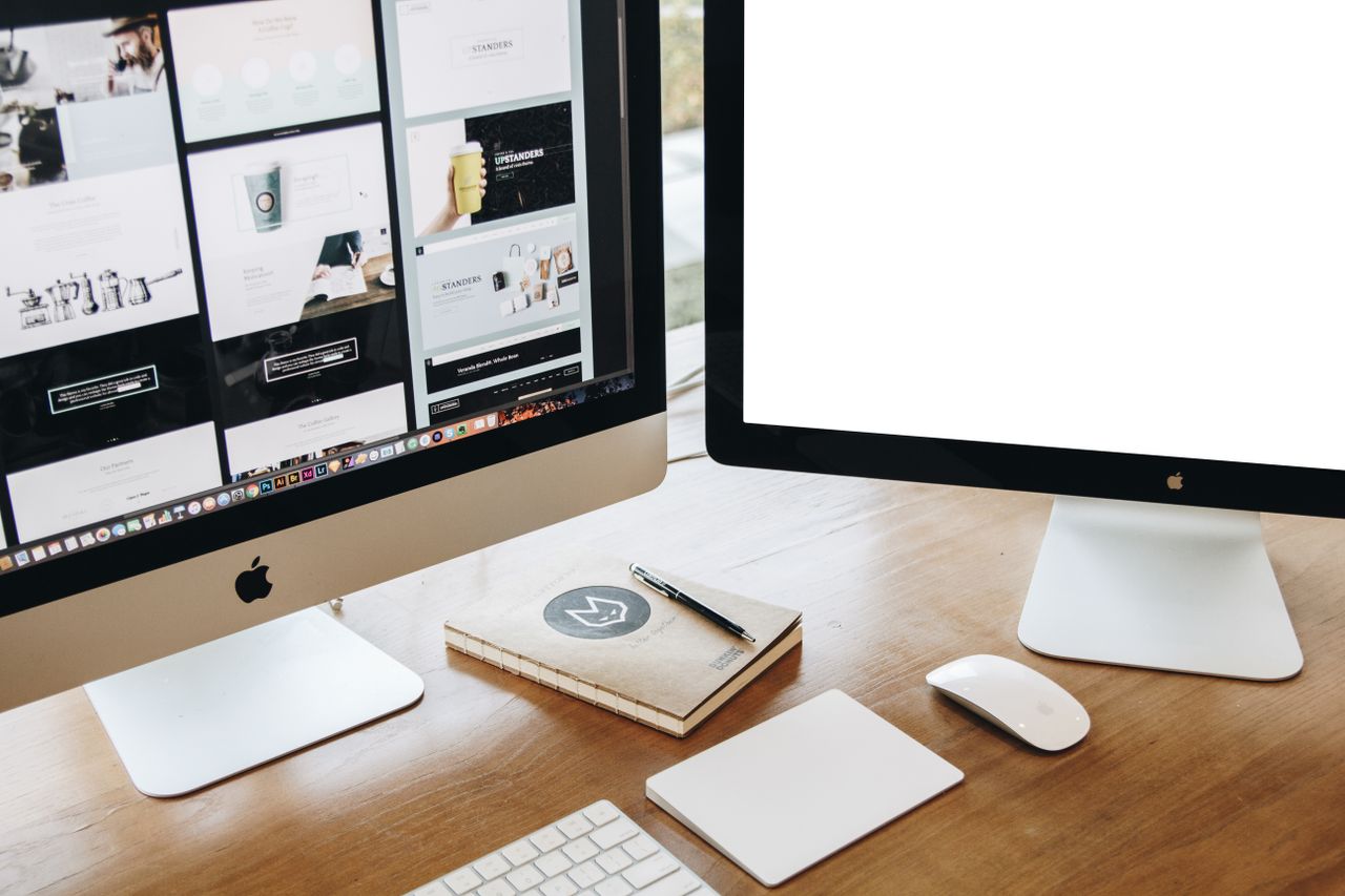 High-angle view of a stylish work desk featuring dual monitors, keyboard, mouse, and modern accessories.